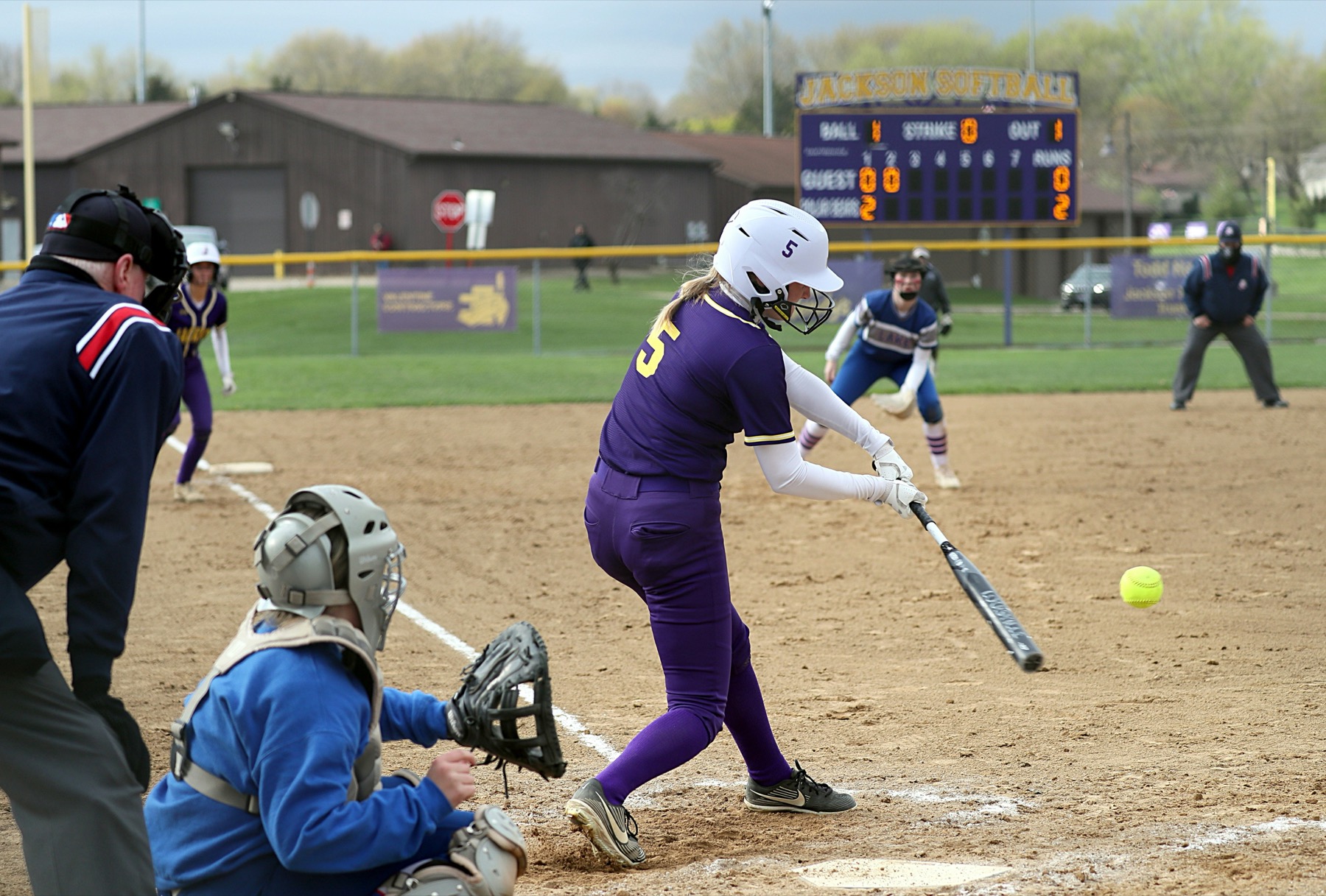 Softball batter making contact near home plate
