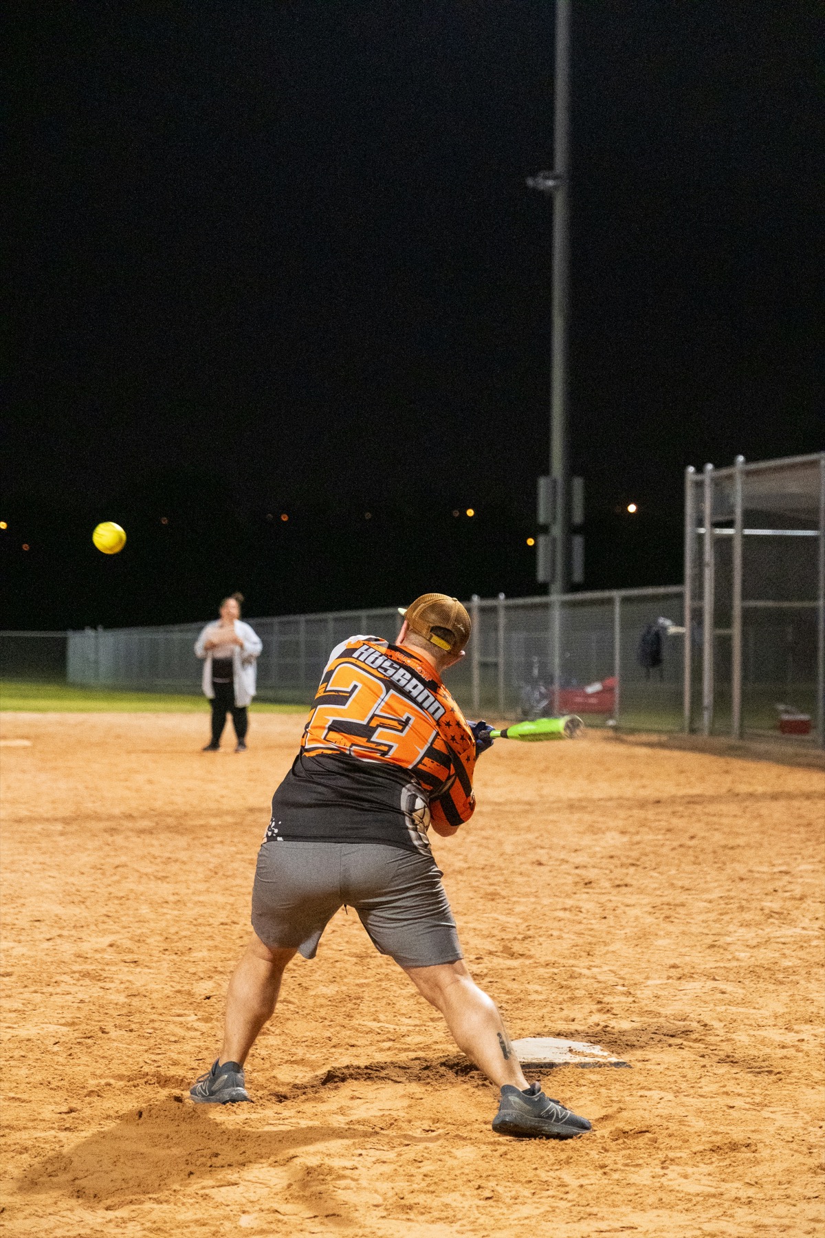 Softball batter swinging under field lights