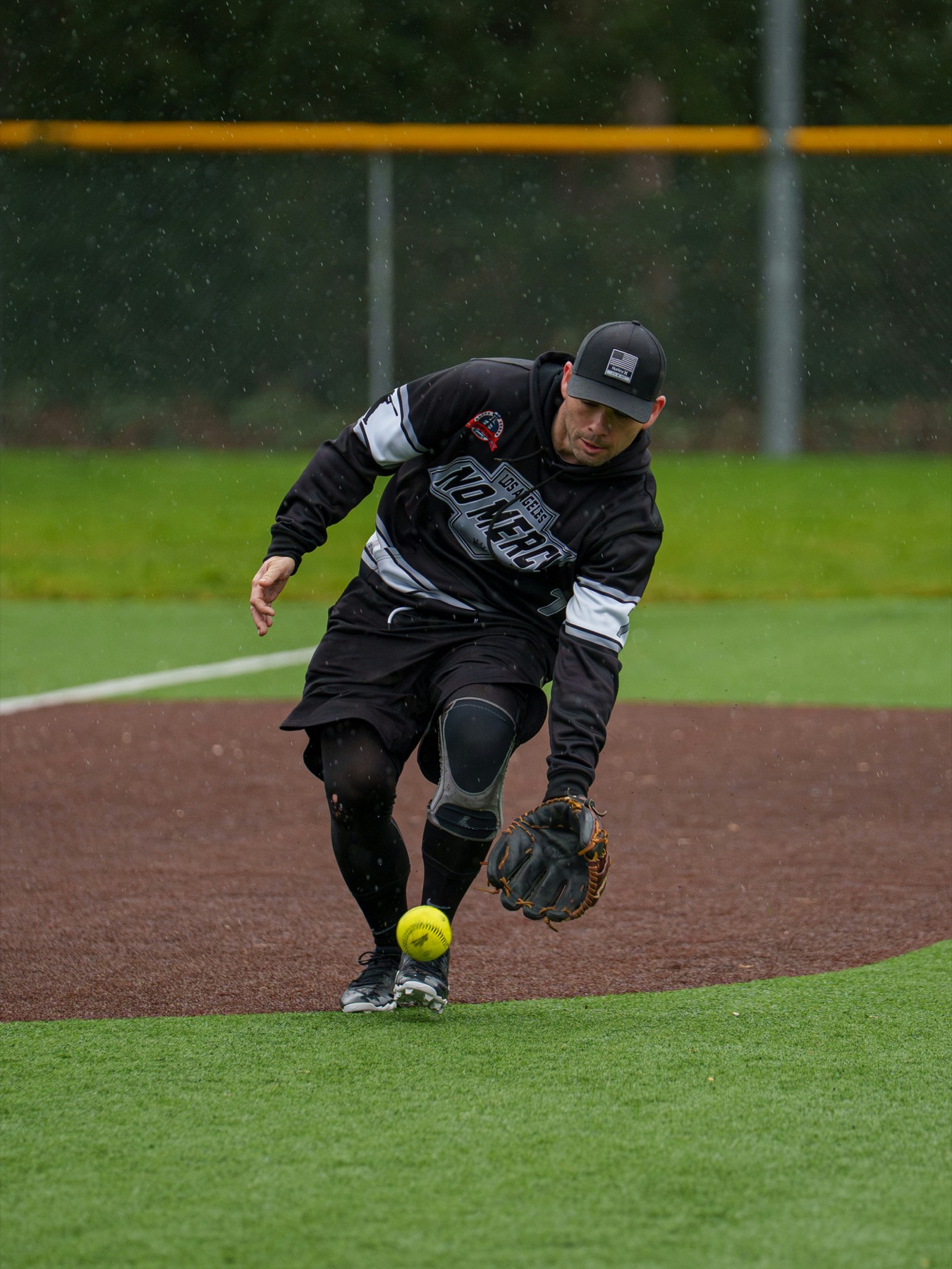 Softball infielder fielding a ground ball in the rain