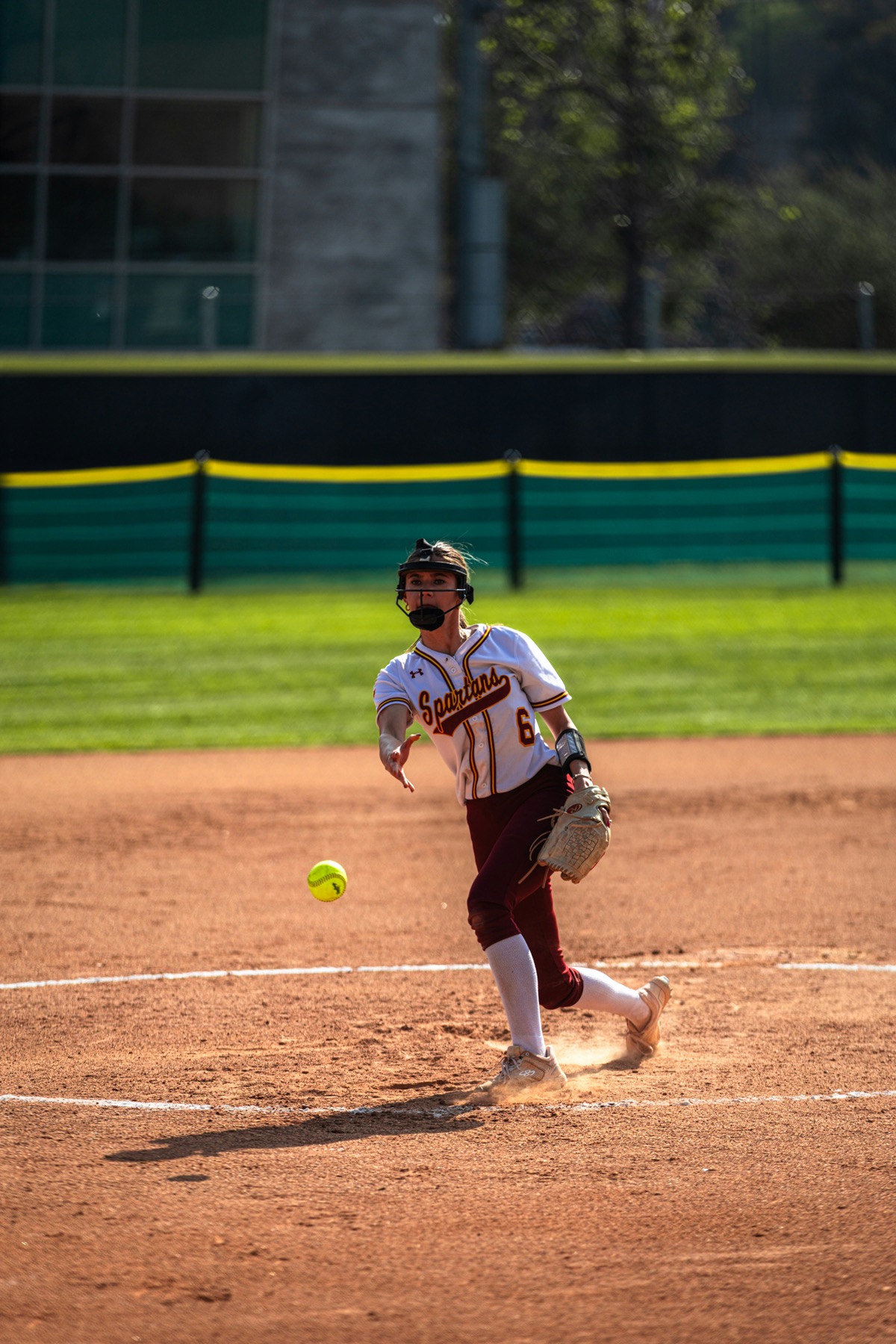 Softball pitcher delivering a pitch on a sunny field